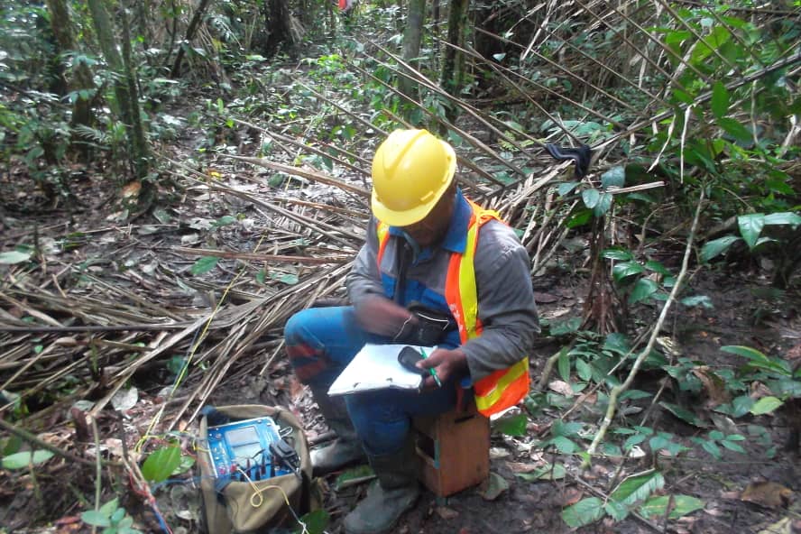 Opérateur géophysicien en relevé de terrain en zone forestière